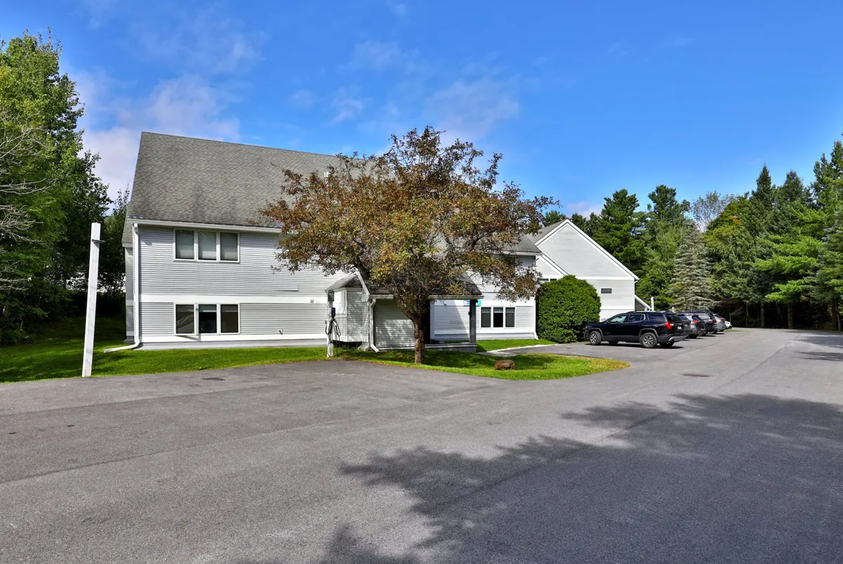 An inviting exterior view of the condo building, highlighted by a leafy tree and well-kept parking area. The scene conveys a welcoming, community-oriented atmosphere that guests return to after a day on the slopes.